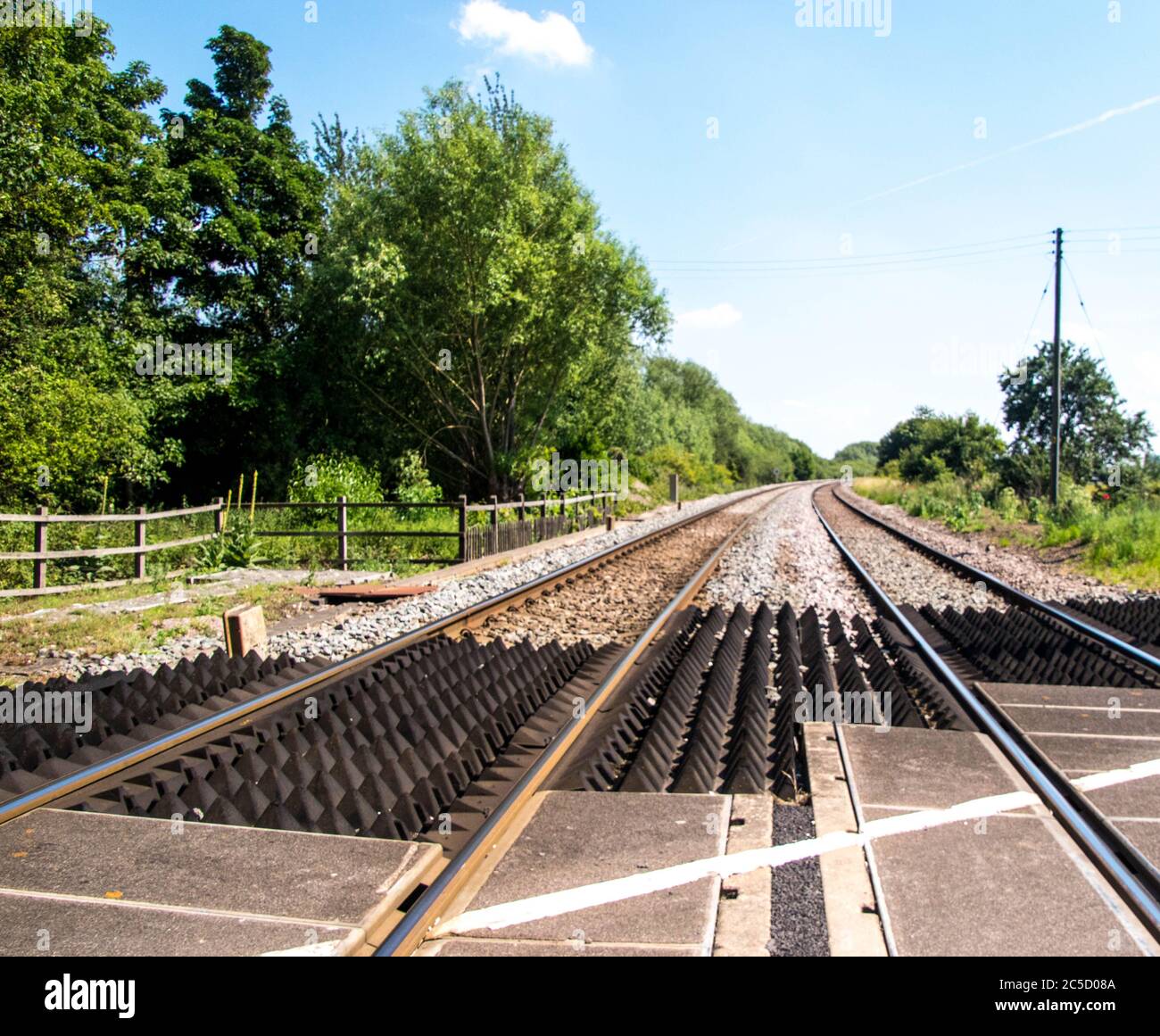 A typical railway line crossing in the United Kingdom, on a dry summer