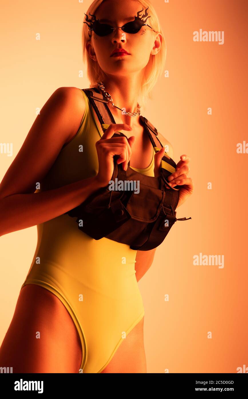 attractive futuristic girl posing in fire-shaped sunglasses on orange Stock Photo