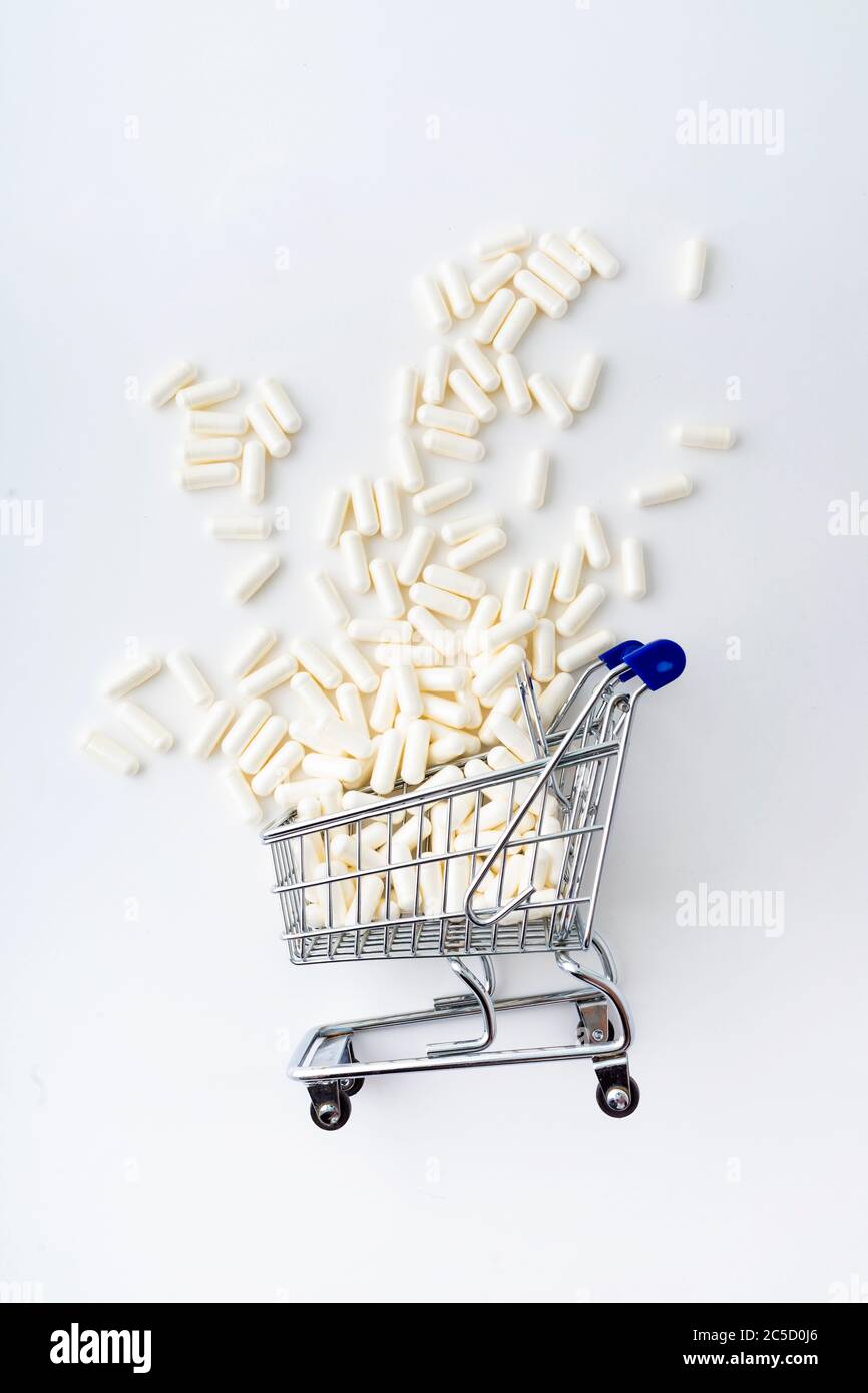 Shopping trolley cart  medicine pills on light background. Creative idea for drugstore, online pharmacy, health behaviors and pharmaceutical company b Stock Photo