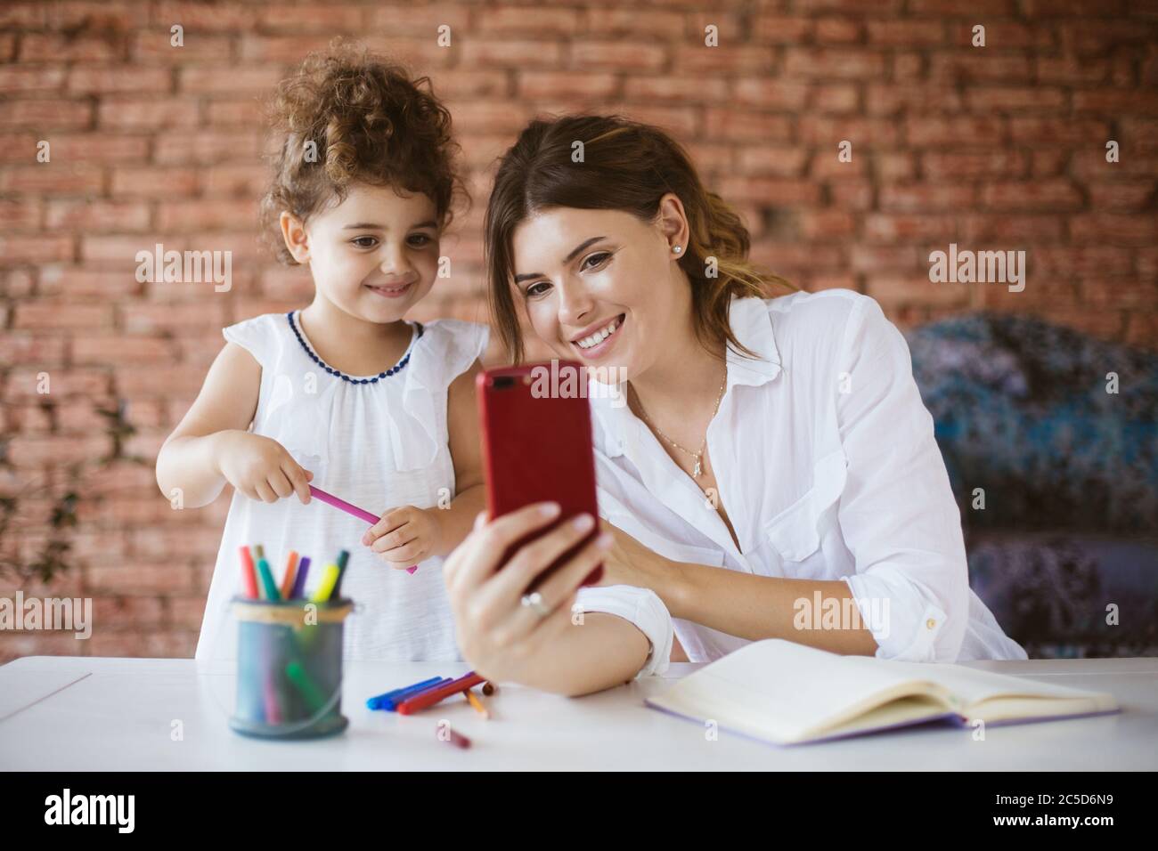 Beautiful young mother and her baby daughter happily taking phot Stock Photo