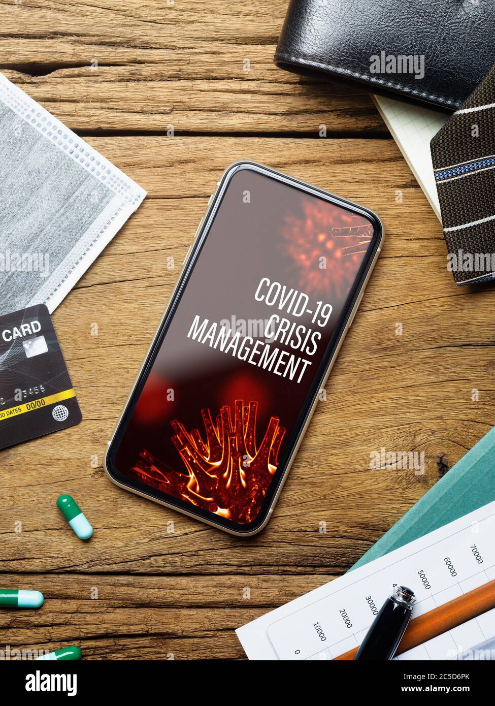 Coronavirus Covid-19 pandemic outbreak Crisis Management background concept. Mockup mobile phone on grunge wood with  business charts, facemask on wor Stock Photo