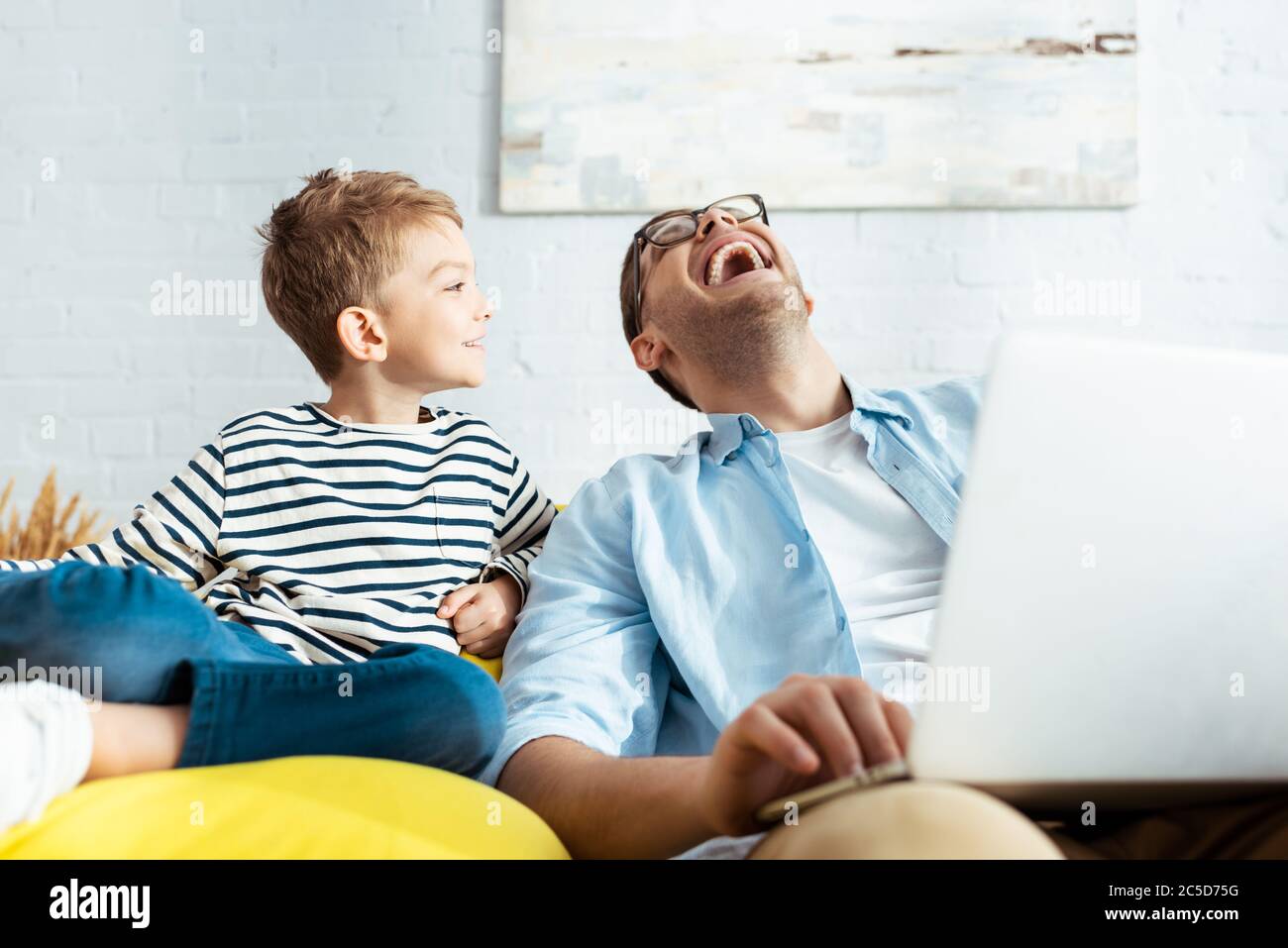 smiling boy looking at happy father using laptop Stock Photo - Alamy