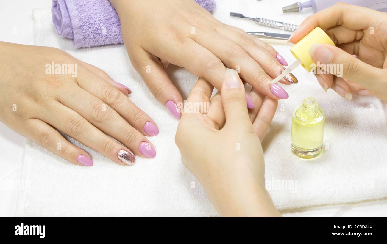 The manicurist applies a moisturizing oil to the cuticle. SPA manicure, procedure, moisturizing. Skin care. Beauty salon. Manicure concept. Beauty nai Stock Photo