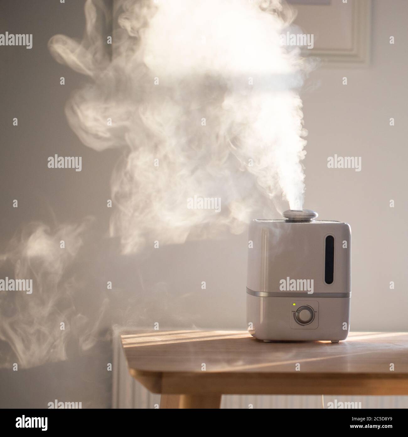 Close up of aroma oil diffuser on the table at home, steam from the air humidifier. Ultrasonic technology, increase in air humidity indoors, comfortab Stock Photo