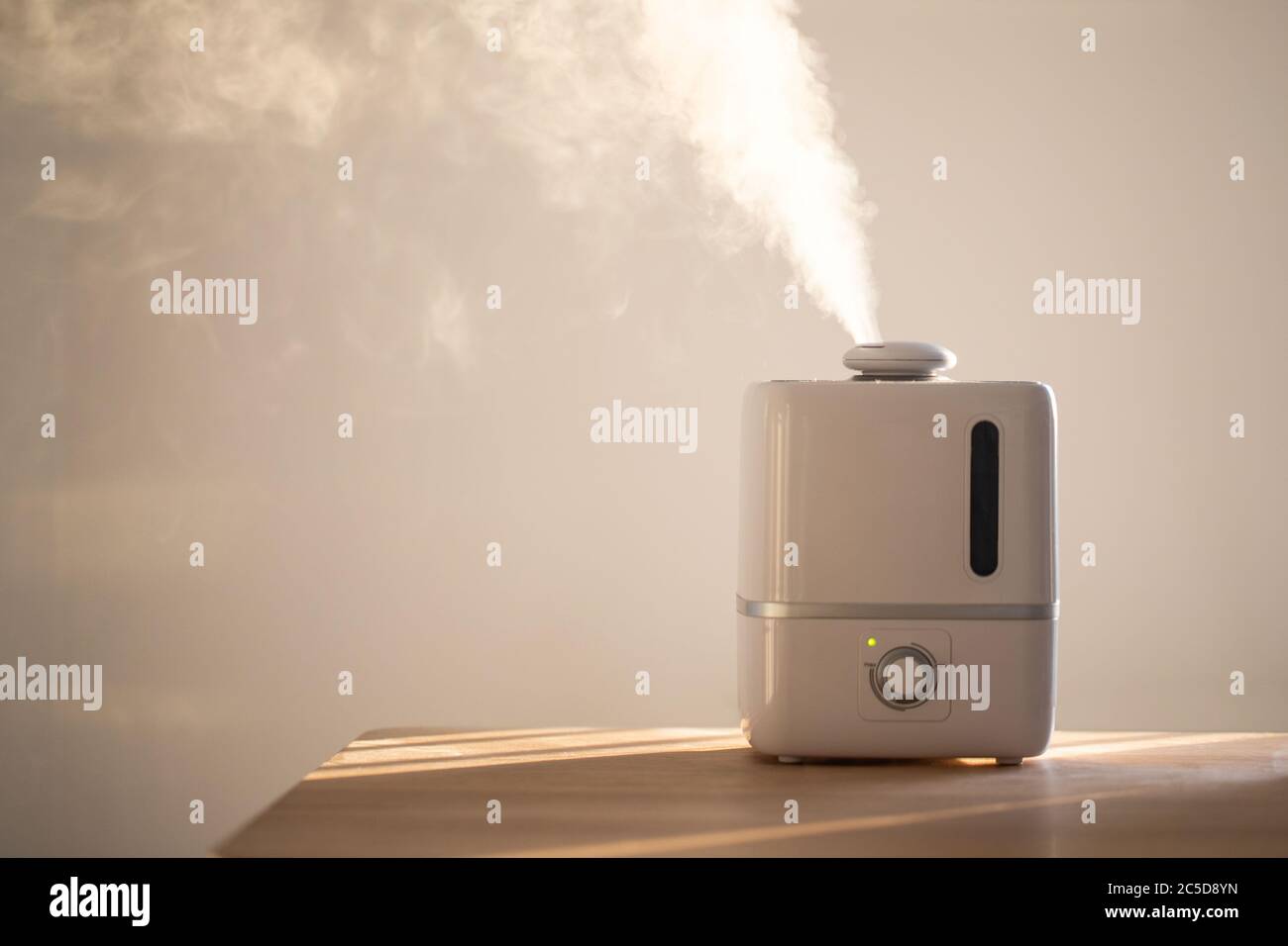 Close up of aroma oil diffuser on the table at home, steam from the air humidifier, copy space. Ultrasonic technology, increase in air humidity indoor Stock Photo