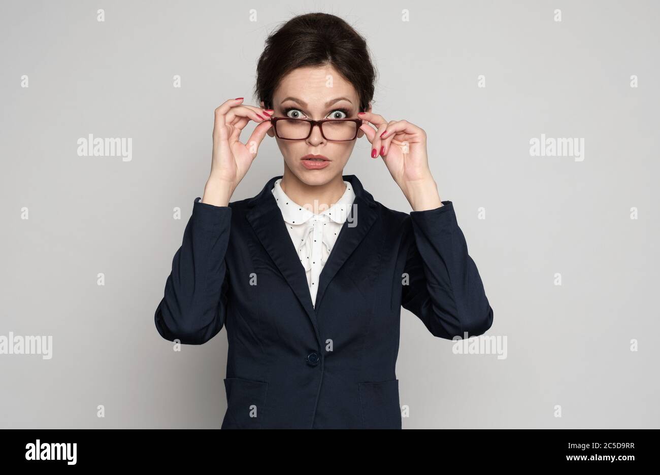 Shocked business woman staring at camera above her eyeglasses Stock Photo