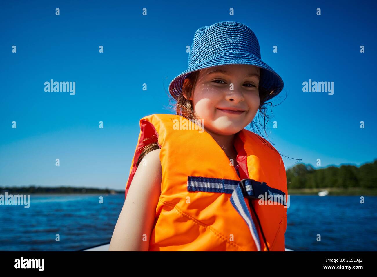 little girl in a swimming vest sits in a motorboat  Stock Photo
