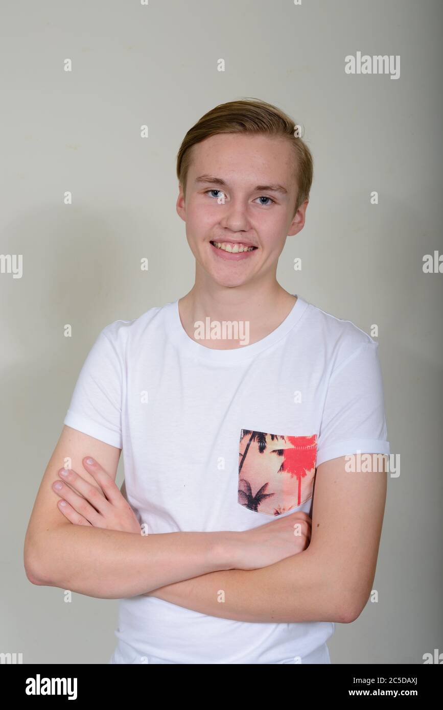 Portrait of happy young handsome blond teenage boy smiling with arms ...