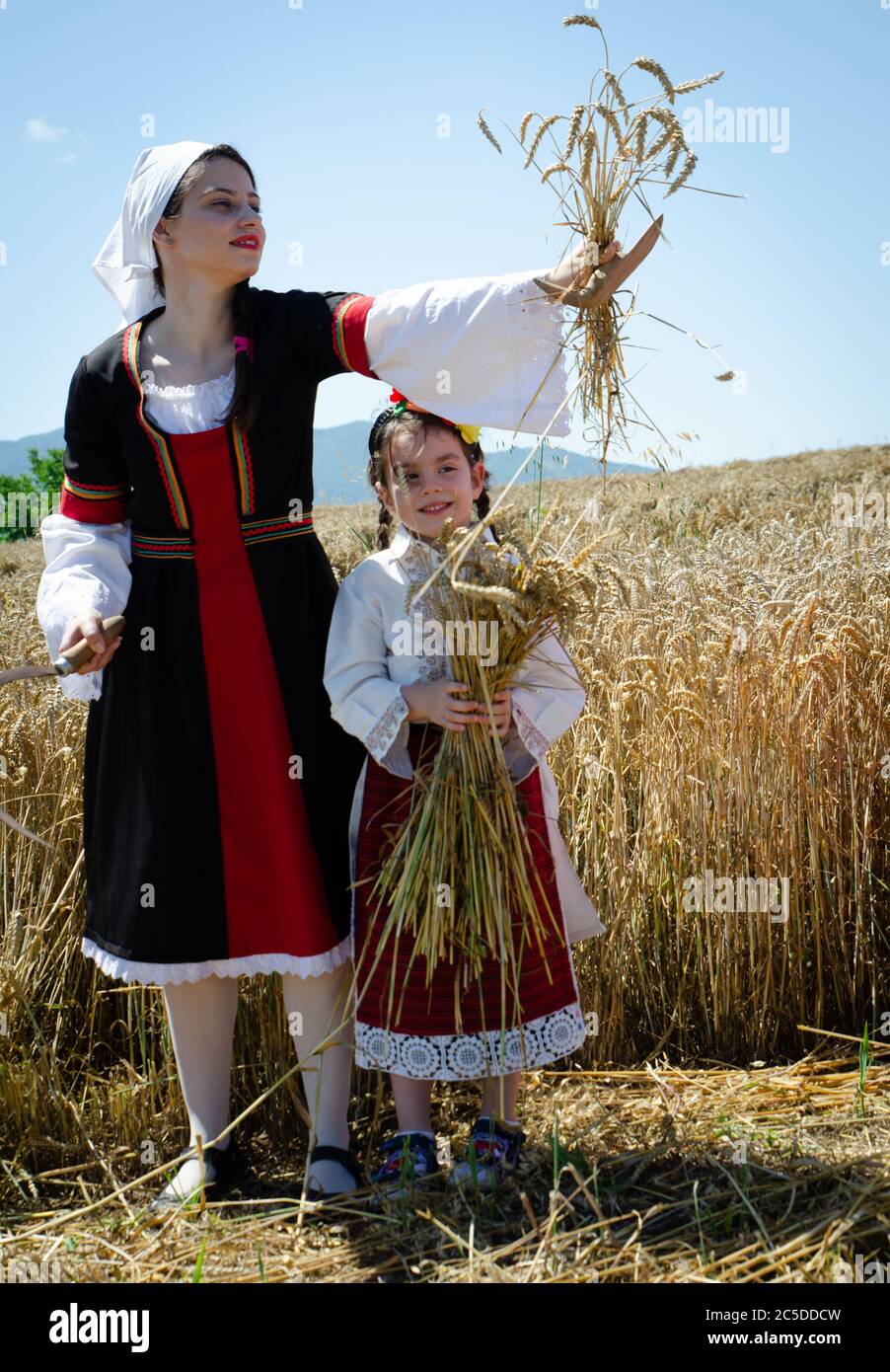 Young Bulgarian women in traditional costume celebrate the harvest festival harvest in countryside village. Stock Photo