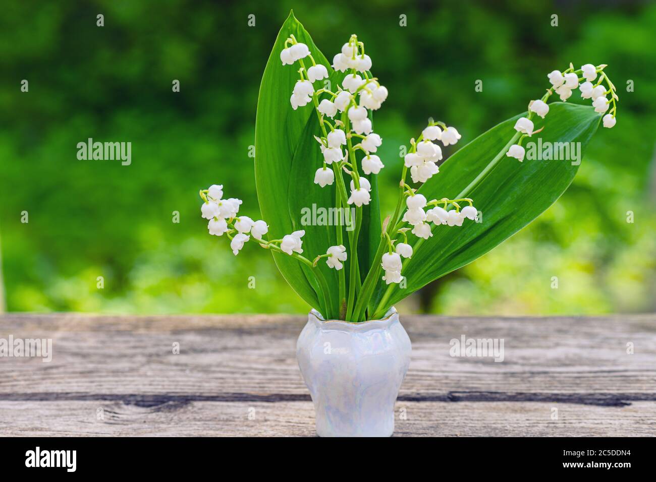 Spring flowers standing bouquet in vase wooden old table. Spring flower lily of the valley. Lily of the valley. Stock Photo