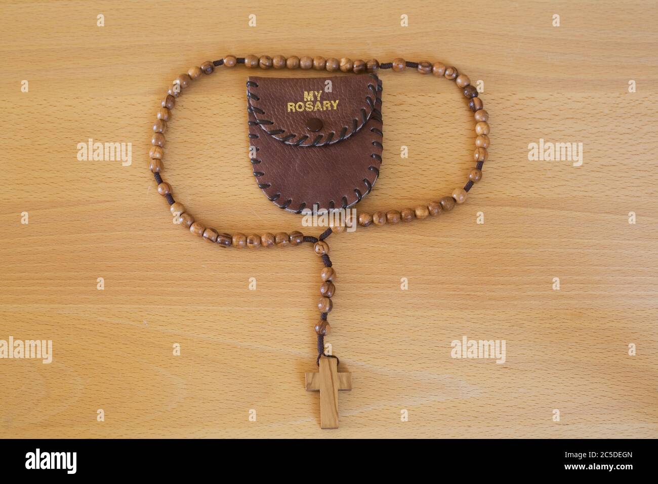 Wooden sets of rosary beads and 'My Rosary' wallet displayed in plain wooden surface Stock Photo