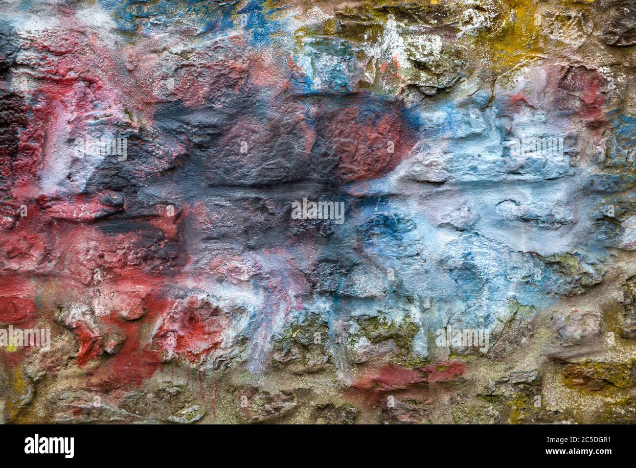 Old abstract red blue multi coloured painted stone brick wall texture background Stock Photo
