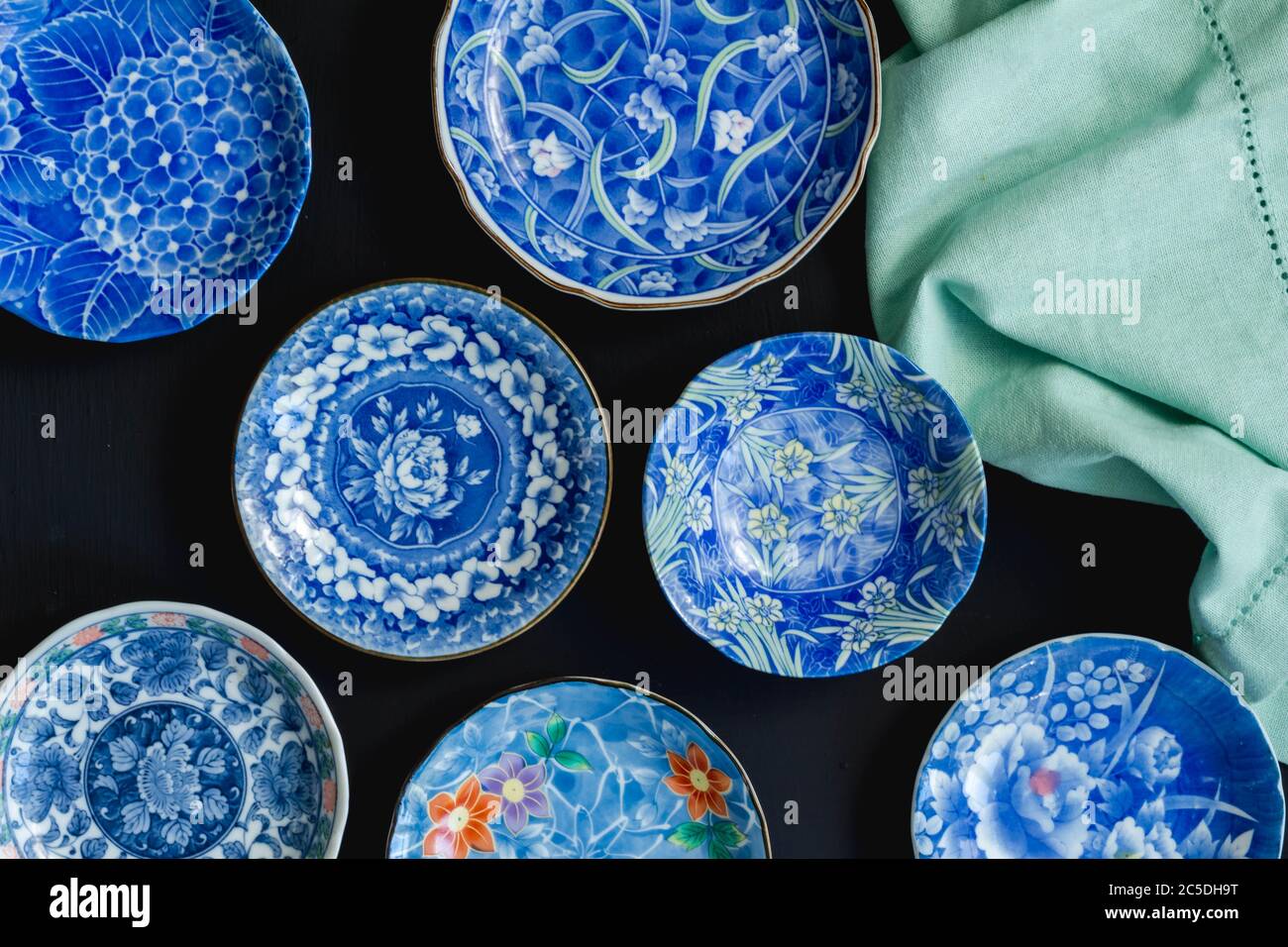 Blue and white decorative Japanese ceramic plates on black background - Top view photo Stock Photo