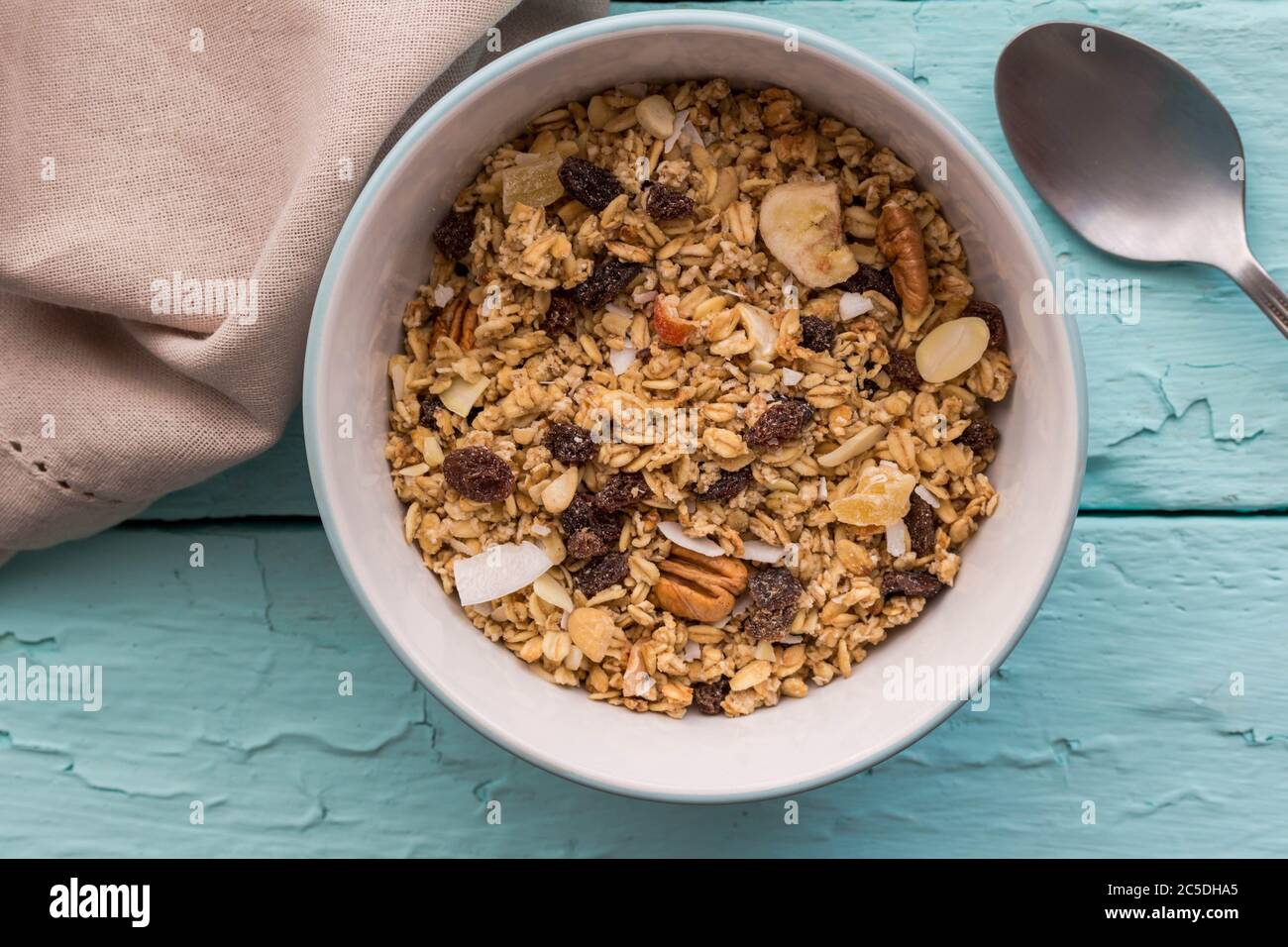 Granola in bowl with raisins,dried banana,  nuts - top view breakfast muesli on rustic blue table background Stock Photo