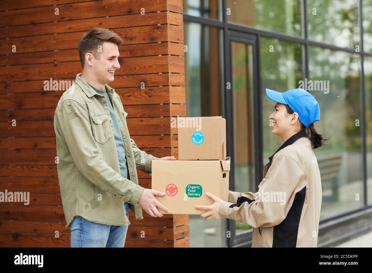 Young man getting his parcels from the courier while they standing outdoors Stock Photo