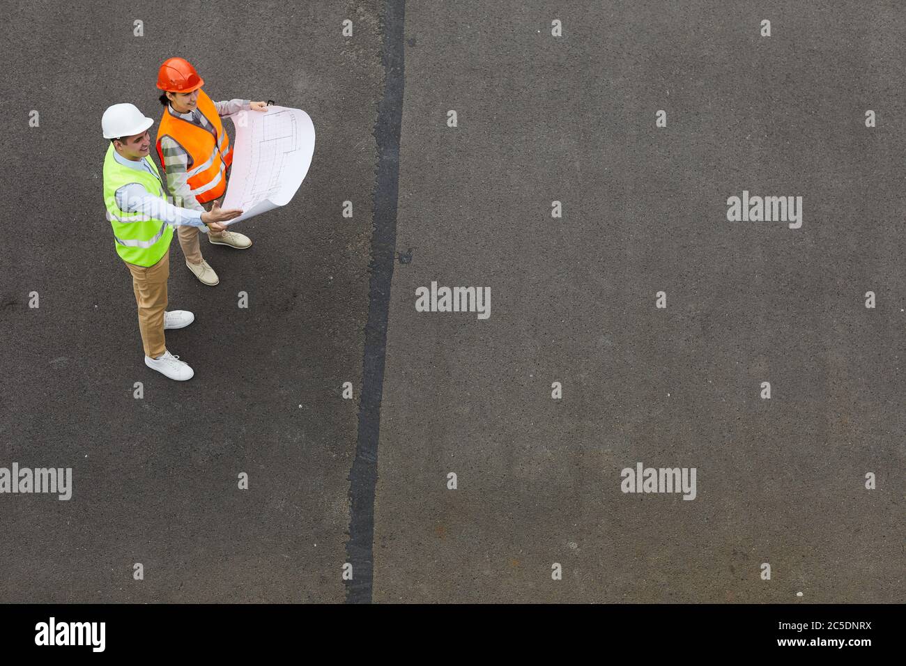 High angle view of two engineers standing outdoors and examining the blueprint of new project Stock Photo