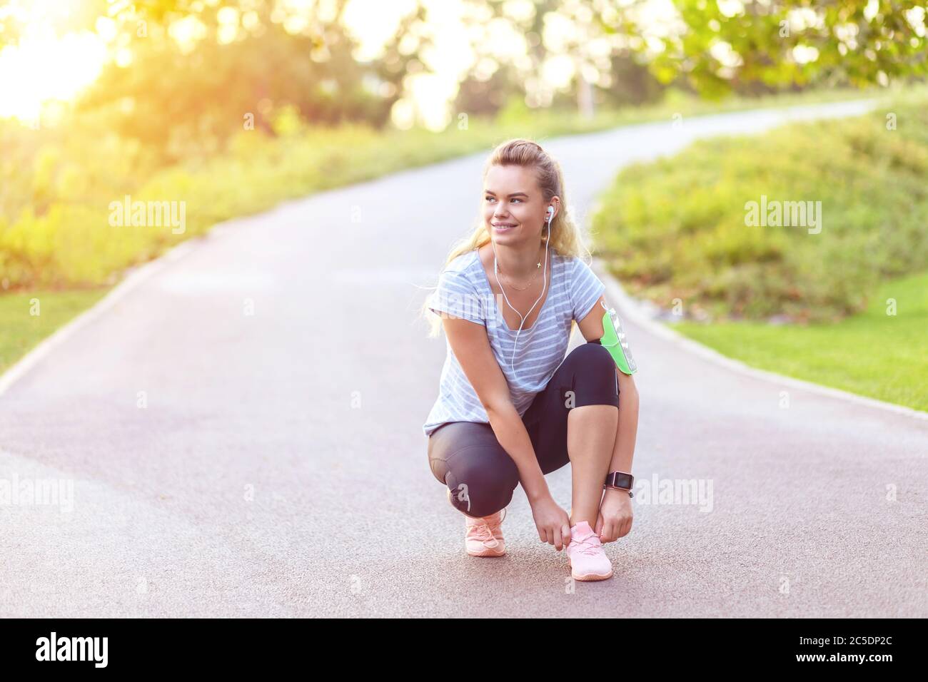 Young fitness woman tie shoelace of sport shoes on city running track Stock Photo