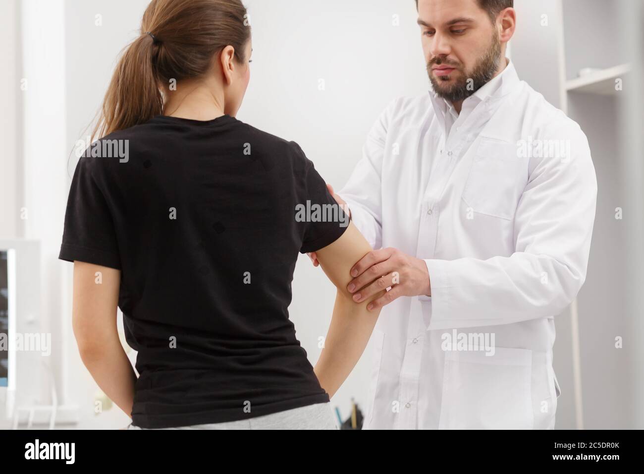 Male doctor examining female patient suffering from elbow pain. Medical