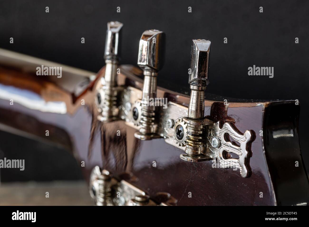 Mechanical keys for tuning the guitar. Metal strings A tuned acoustic guitar. Guitar lessons. Chrome details of the musical instrument. Stock Photo