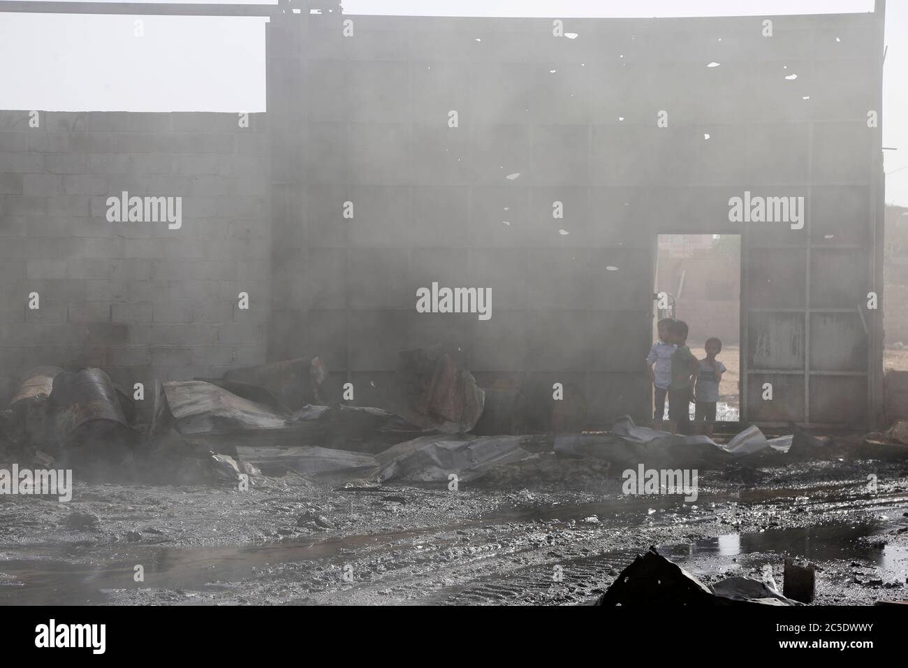 Sanaa, Yemen. 2nd July, 2020. Children look at a warehouse after it was hit by airstrikes in Sanaa, Yemen, on July 2, 2020. The Saudi-led coalition on Wednesday launched a series of airstrikes on the Yemeni capital Sanaa, which is under Houthi control, the Houthi-run al-Masirah TV reported. Credit: Mohammed Mohammed/Xinhua/Alamy Live News Stock Photo