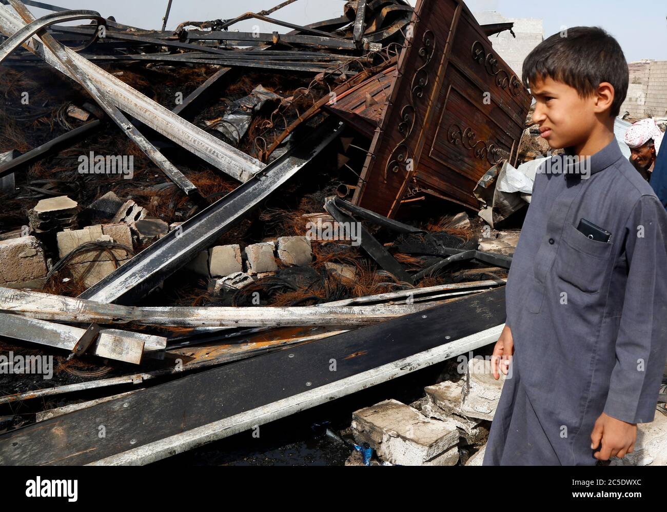 Sanaa, Yemen. 2nd July, 2020. A boy looks at a warehouse after it was hit by airstrikes in Sanaa, Yemen, on July 2, 2020. The Saudi-led coalition on Wednesday launched a series of airstrikes on the Yemeni capital Sanaa, which is under Houthi control, the Houthi-run al-Masirah TV reported. Credit: Mohammed Mohammed/Xinhua/Alamy Live News Stock Photo