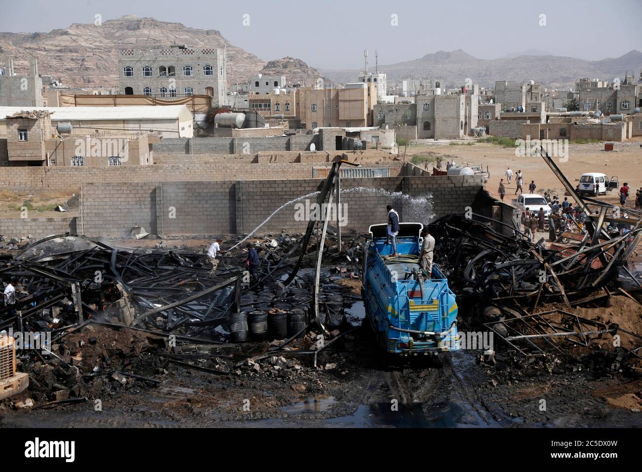 Sanaa, Yemen. 2nd July, 2020. People try to extinguish a fire following airstrikes on a warehouse in Sanaa, Yemen, on July 2, 2020. The Saudi-led coalition on Wednesday launched a series of airstrikes on the Yemeni capital Sanaa, which is under Houthi control, the Houthi-run al-Masirah TV reported. Credit: Mohammed Mohammed/Xinhua/Alamy Live News Stock Photo