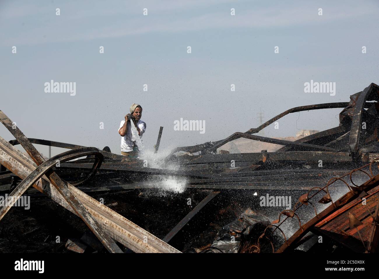 Sanaa, Yemen. 2nd July, 2020. A man tries to extinguish a fire following airstrikes on a warehouse in Sanaa, Yemen, on July 2, 2020. The Saudi-led coalition on Wednesday launched a series of airstrikes on the Yemeni capital Sanaa, which is under Houthi control, the Houthi-run al-Masirah TV reported. Credit: Mohammed Mohammed/Xinhua/Alamy Live News Stock Photo