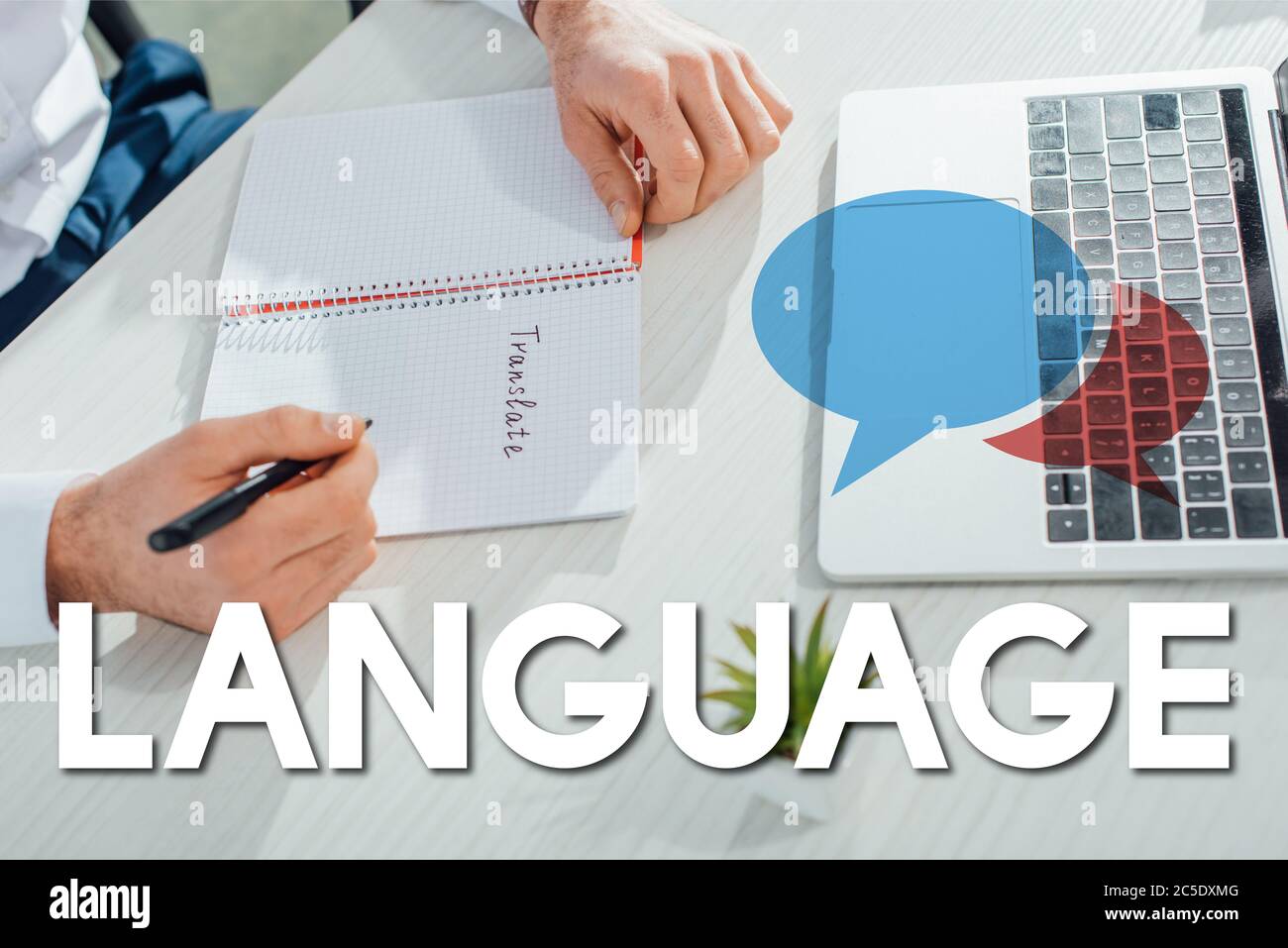 partial view of translator writing in notepad in office with laptop and