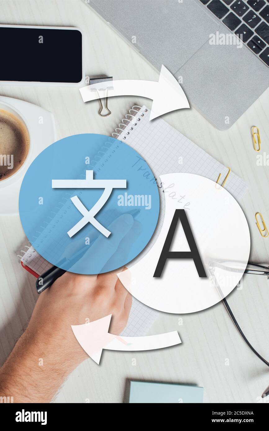 partial view of translator working with notepad, laptop and smartphone ...