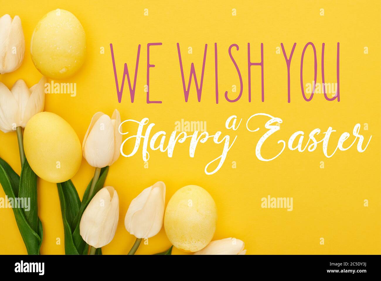 top view of tulips and painted Easter eggs on colorful yellow ...