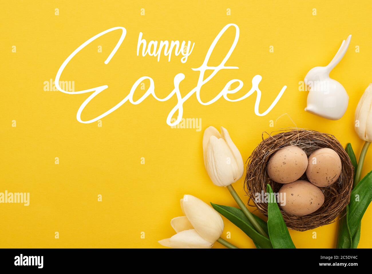 top view of tulips and chicken eggs in nest near Easter bunny on ...
