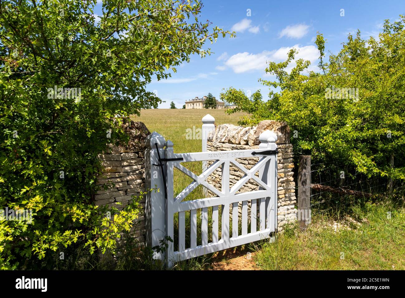 A glimpse of a classical country house built since 2012 on the Farmcote Estate viewed from Campden Lane on the Cotswold Hills, Gloucestershire UK. Stock Photo