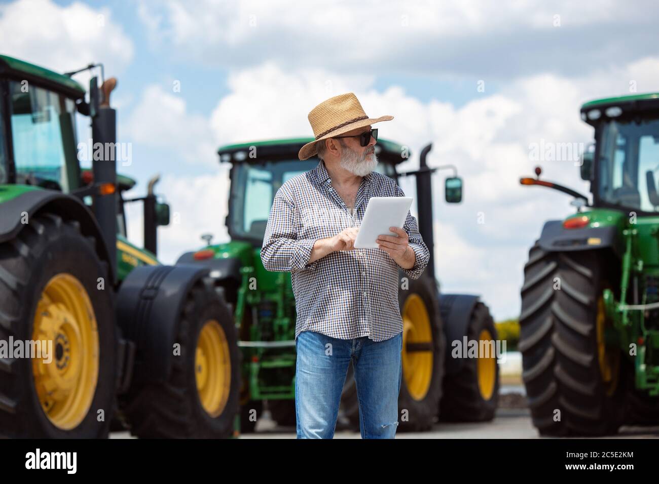 Professional farmer with a modern tractor at work with tablet. Looks ...