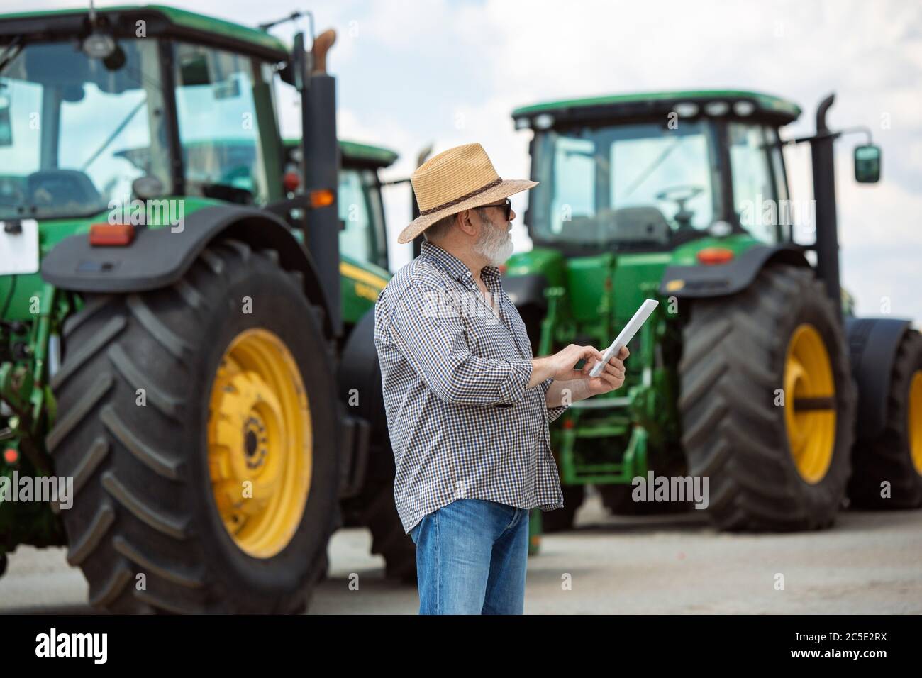 Professional farmer with a modern tractor at work with tablet. Looks ...