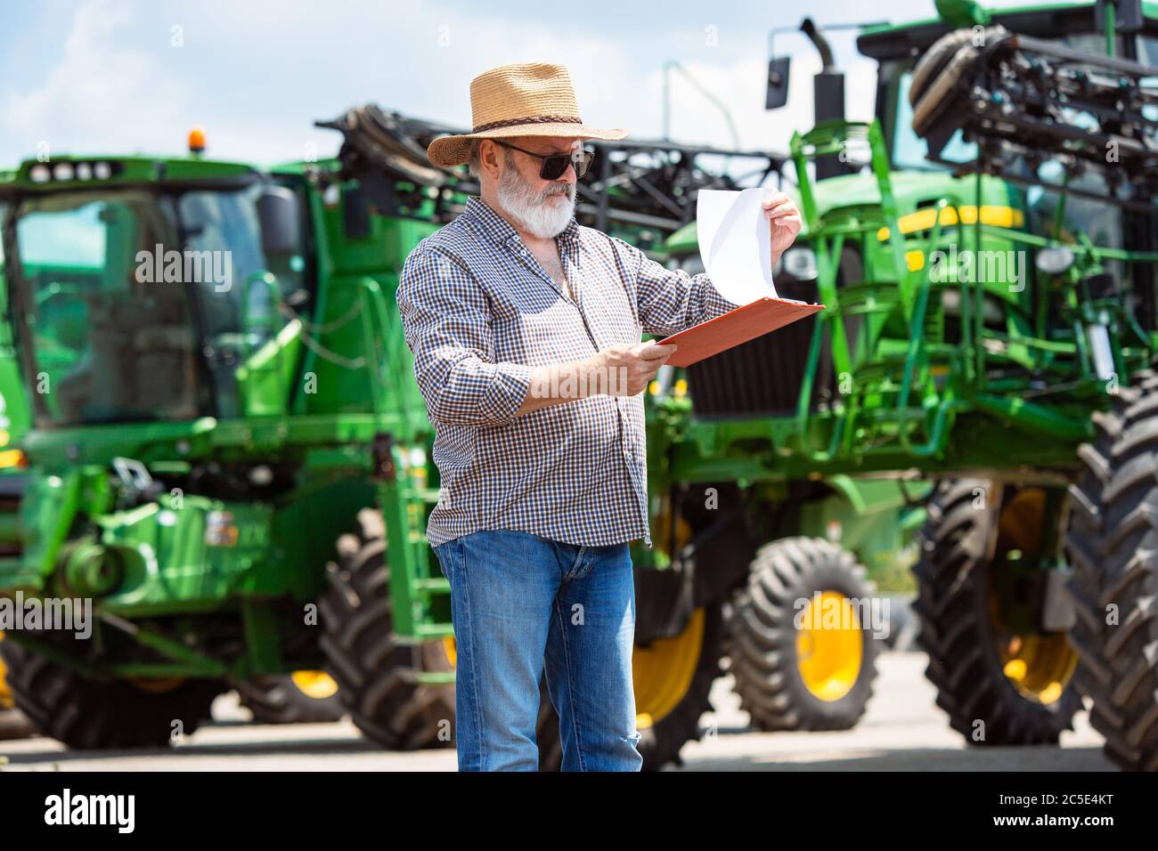 Professional farmer with a modern tractor at work with documents. Looks ...
