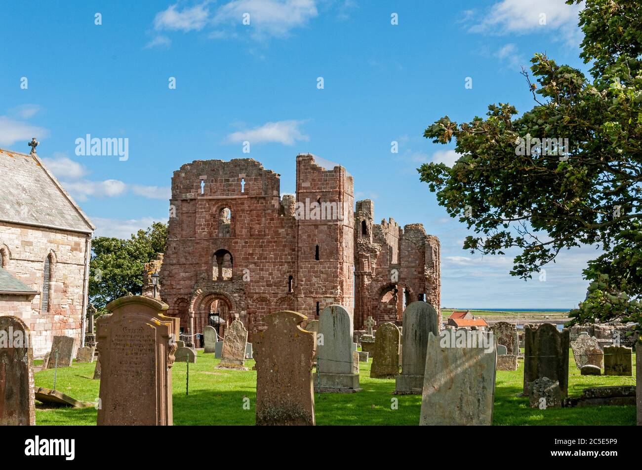 The imposing fortified west doorway of the dark red sandstone church of Lindisfarne Priory with one tower still standing and crossbow loops visible Stock Photo