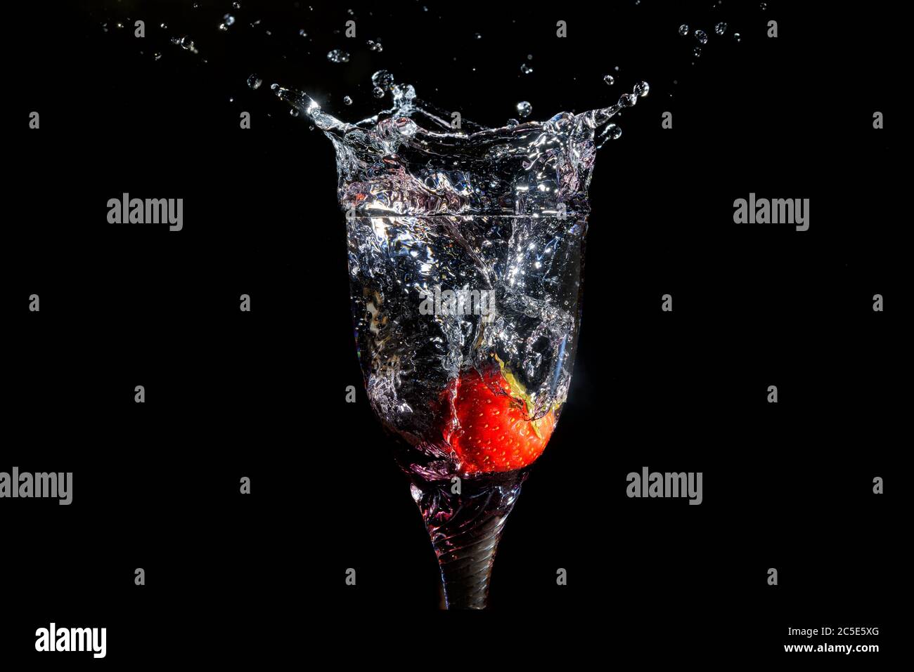 Strawberry splashing into glass on a black backround Stock Photo