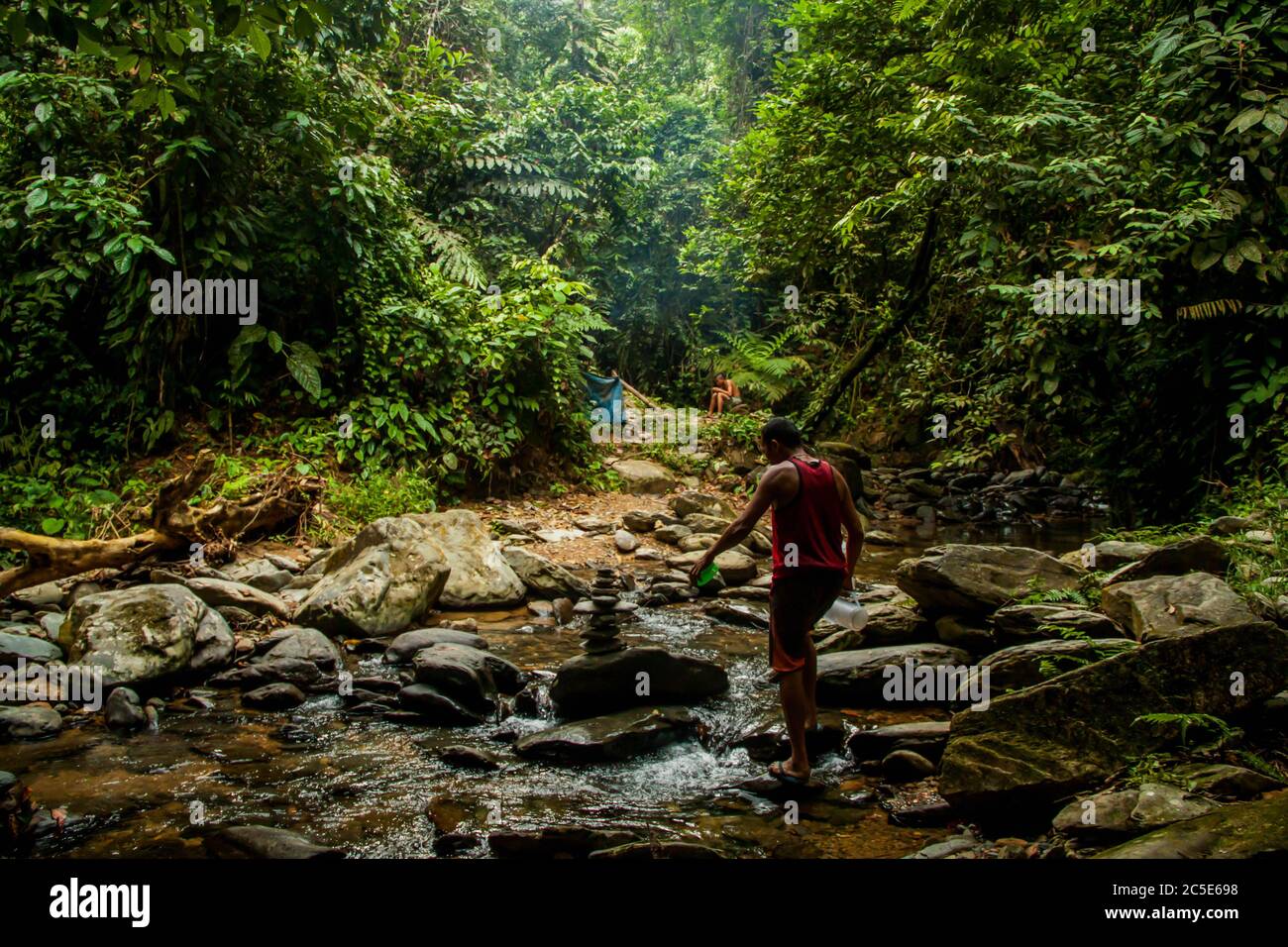 Local man crossing the river in the rainforest Stock Photo