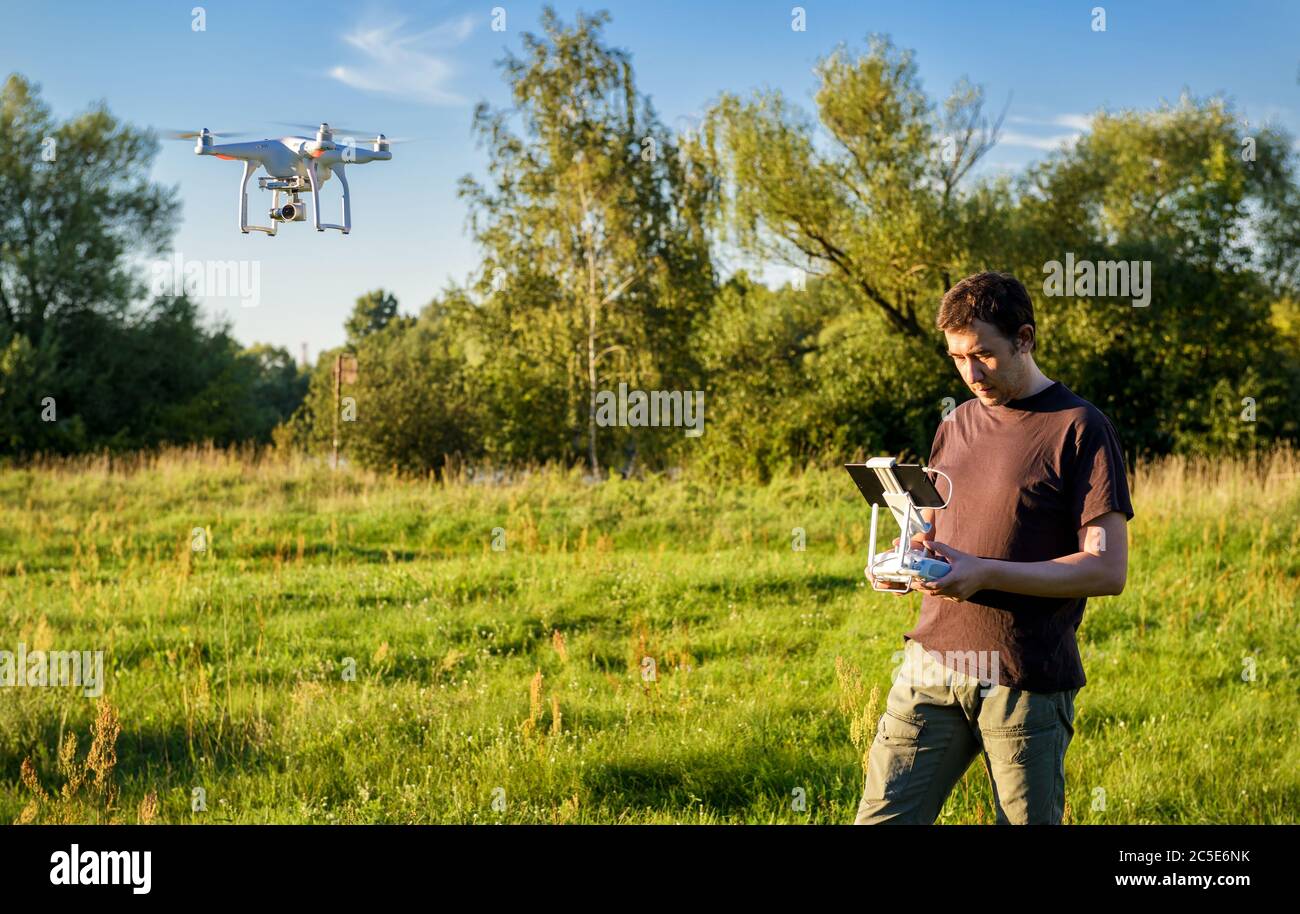 Man operating a drone quad copter with onboard digital camera in the park Stock Photo