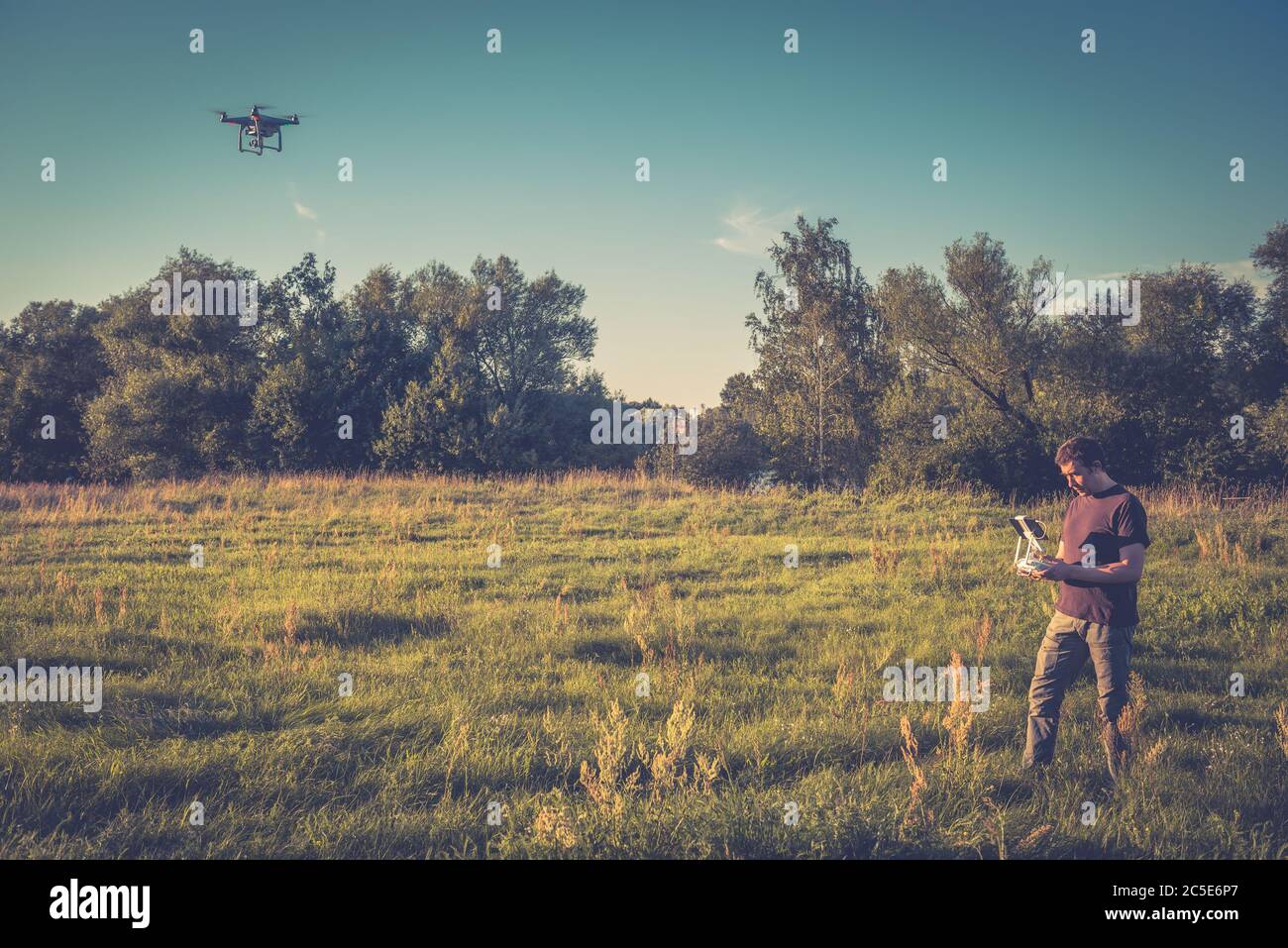 Man operating a drone quad copter with onboard digital camera in a park Stock Photo