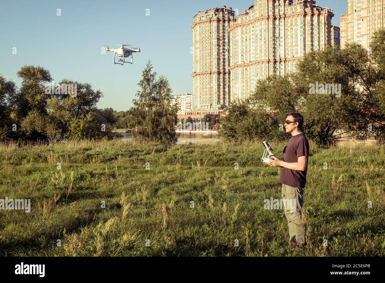 Man operating a drone quad copter with onboard digital camera in the city park Stock Photo