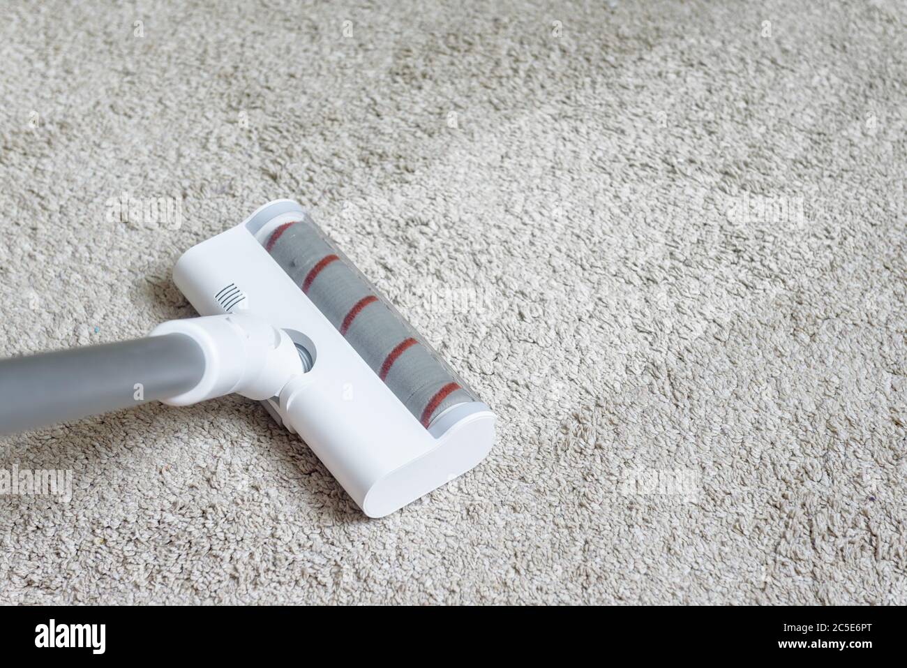 Vacuum cleaner head on dirty carpet with clean strip. Housework with using hoover. Turbo brush of modern vacuum cleaner close up. Home cleaning and ca Stock Photo