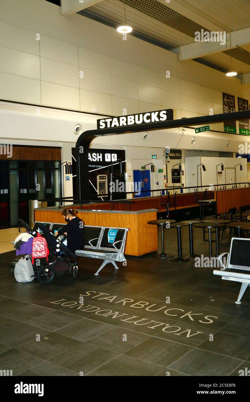 2nd July 2020, Luton Airport, UK A passenger wearing a face mask sits