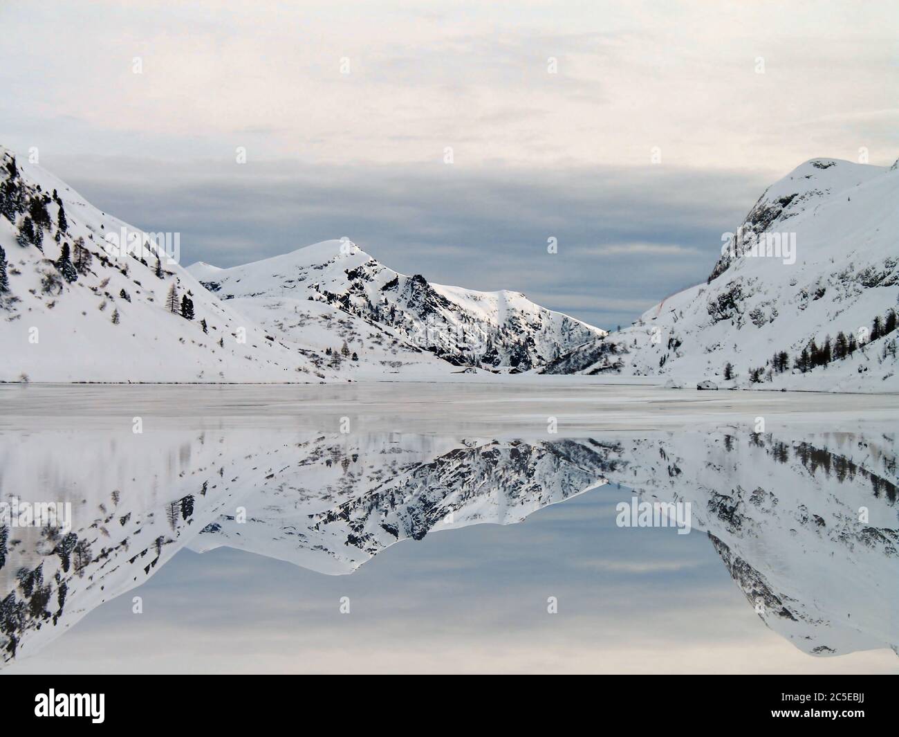 The peace of the cloudy afternoon on the shore of an uncontaminated snowy mountain lake Stock Photo