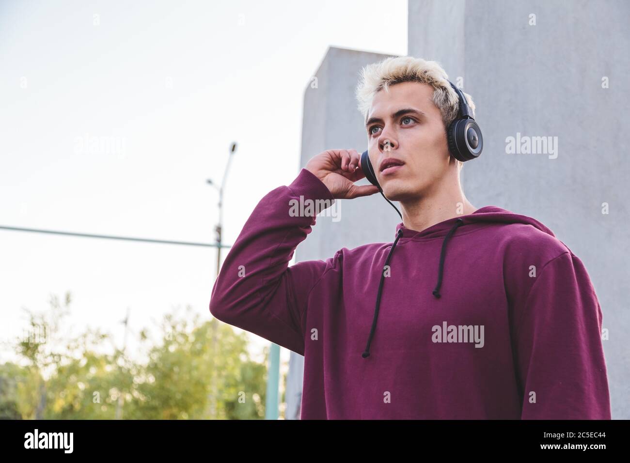 Young sports man in hoodie with headphones on work out area Stock Photo