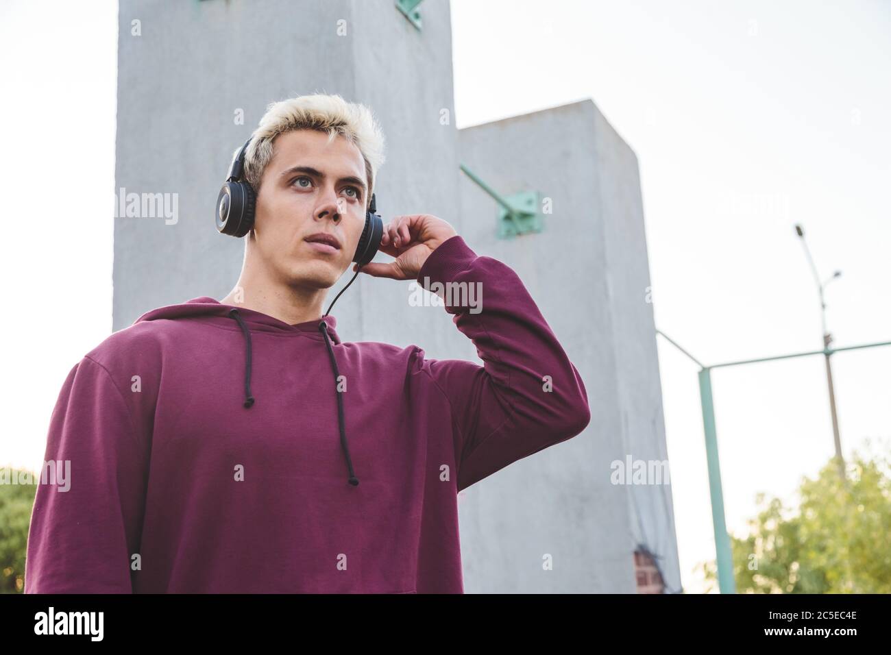 Young sports man in hoodie with headphones on work out area Stock Photo