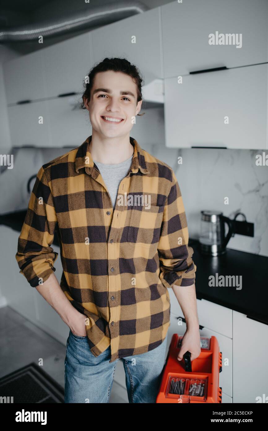 Handyman holding tools standing in kitchen, professional plumbing