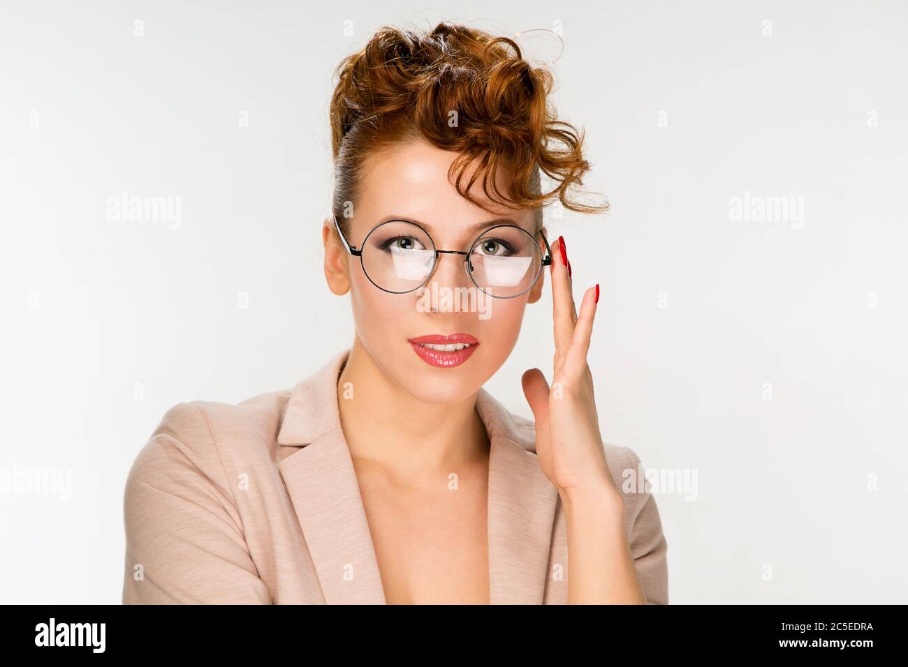 Closeup of attractive young woman isolated on gray background wearing big round spectacles with thin black frame touching specks with fingers smili Stock Photo Alamy