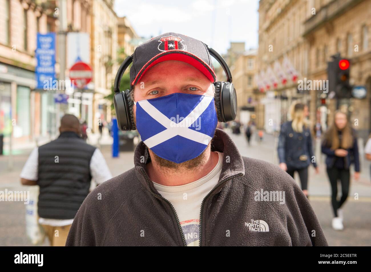 Glasgow, Scotland, UK. 2nd July, 2020. Pictured: A man seen wearing a St Andrews Scotland Flag design face mask. Scenes from Glasgows style mile, Buchanan Street shopping area, where more people are seen wearing face masks or home made face coverings. Nicola Sturgeon announced earlier today that wearing a face covering is to become mandatory in shops from 10th July next week. Face coverings are already mandatory when taking public transport in a bid to slow down the spread of coronavirus. Credit: Colin Fisher/Alamy Live News Stock Photo