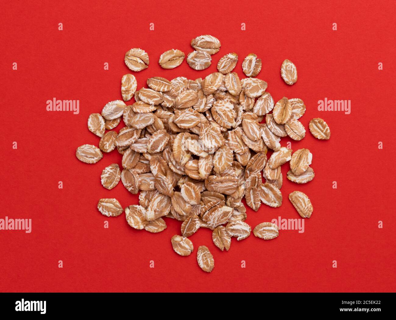 Rye flakes on red color background, top view Stock Photo